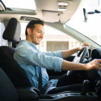 istockphoto-1303145841-612x612 Handsome man in his 30s sitting in the driver's seat and smiling. Taxi driver listening to music on the car and changing the radio station